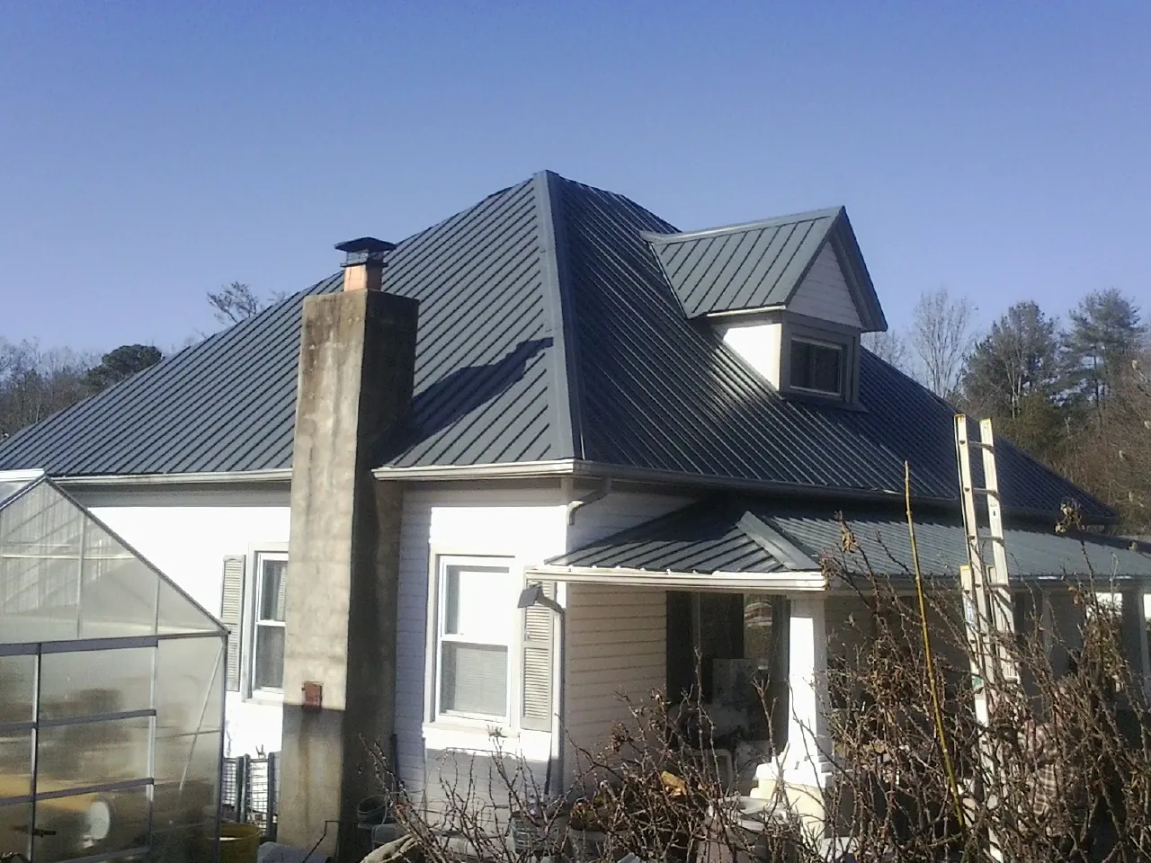 Dark blue standing seam metal roof on a white farmhouse with dormer — Slate & Tile Roof Repair by Roofing Brothers in Longford