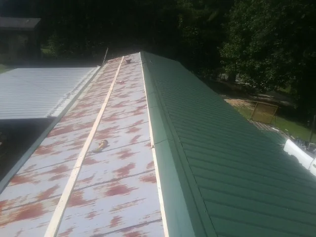 Old rusted panels beside newly installed green metal roofing — Wind Damage Roof Repair by Roofing Brothers in Longford