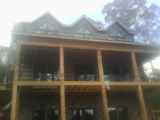 Dormers and porch framing on a large log home under construction — Roof Coating work by our crew in Longford