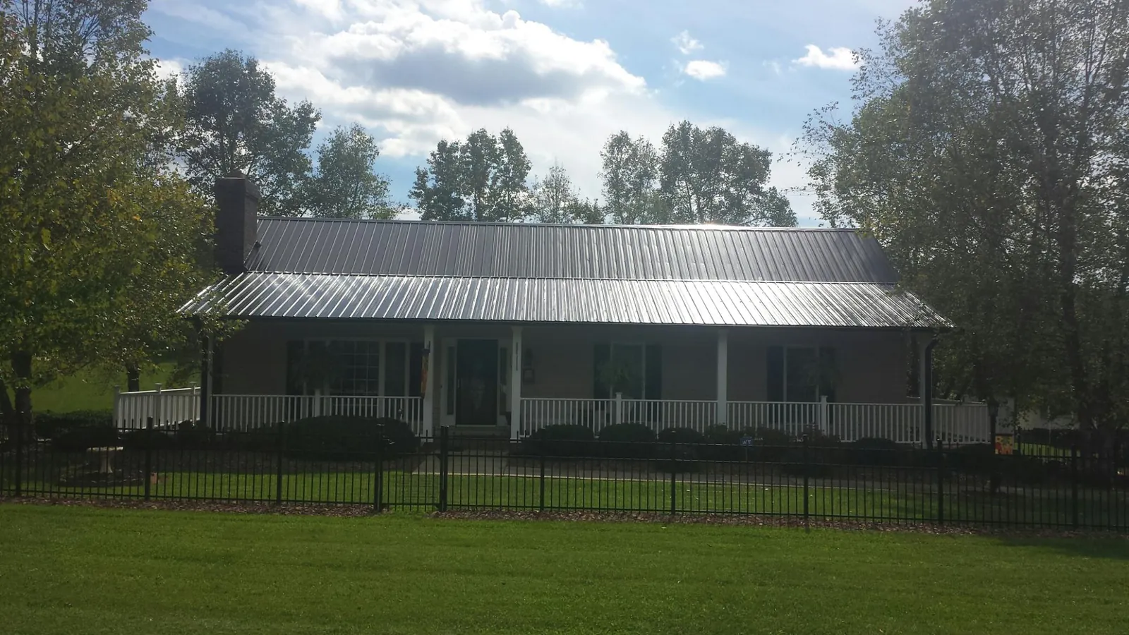 Gray metal roof on a brick ranch with a full width front porch — Gutter Guard Installation work by our crew in Longford
