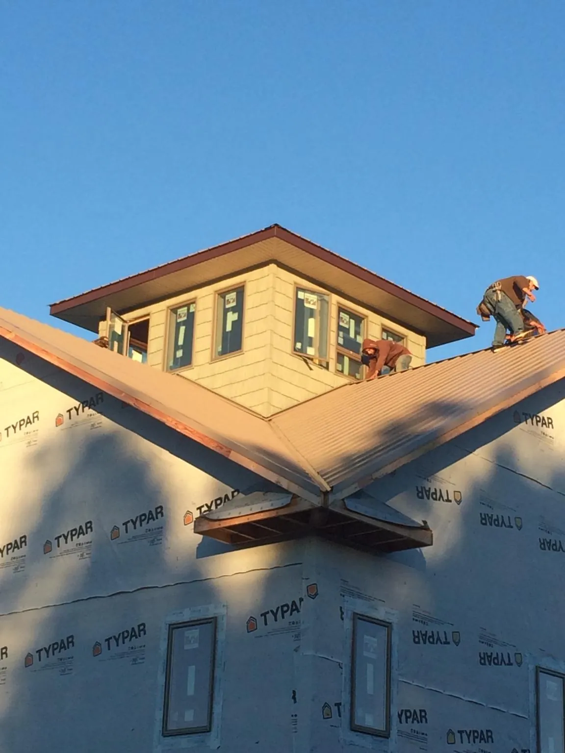 Roofers working around a rooftop cupola on a new metal roof at sunset — Roof Waterproofing in Longford by Roofing Brothers